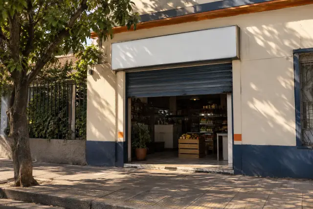 Fachada de un local comercial de barrio con la cortina abierta por la mañana